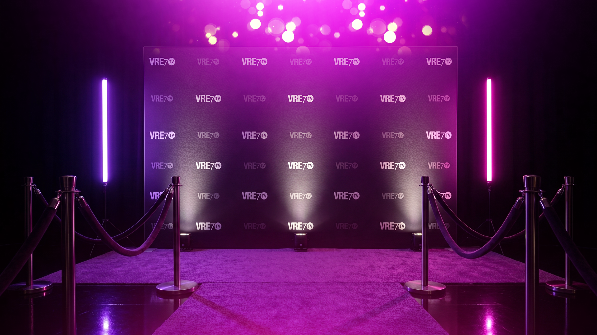 VRE7 TV step-and-repeat backdrop glowing in magenta light behind velvet ropes on the carpet