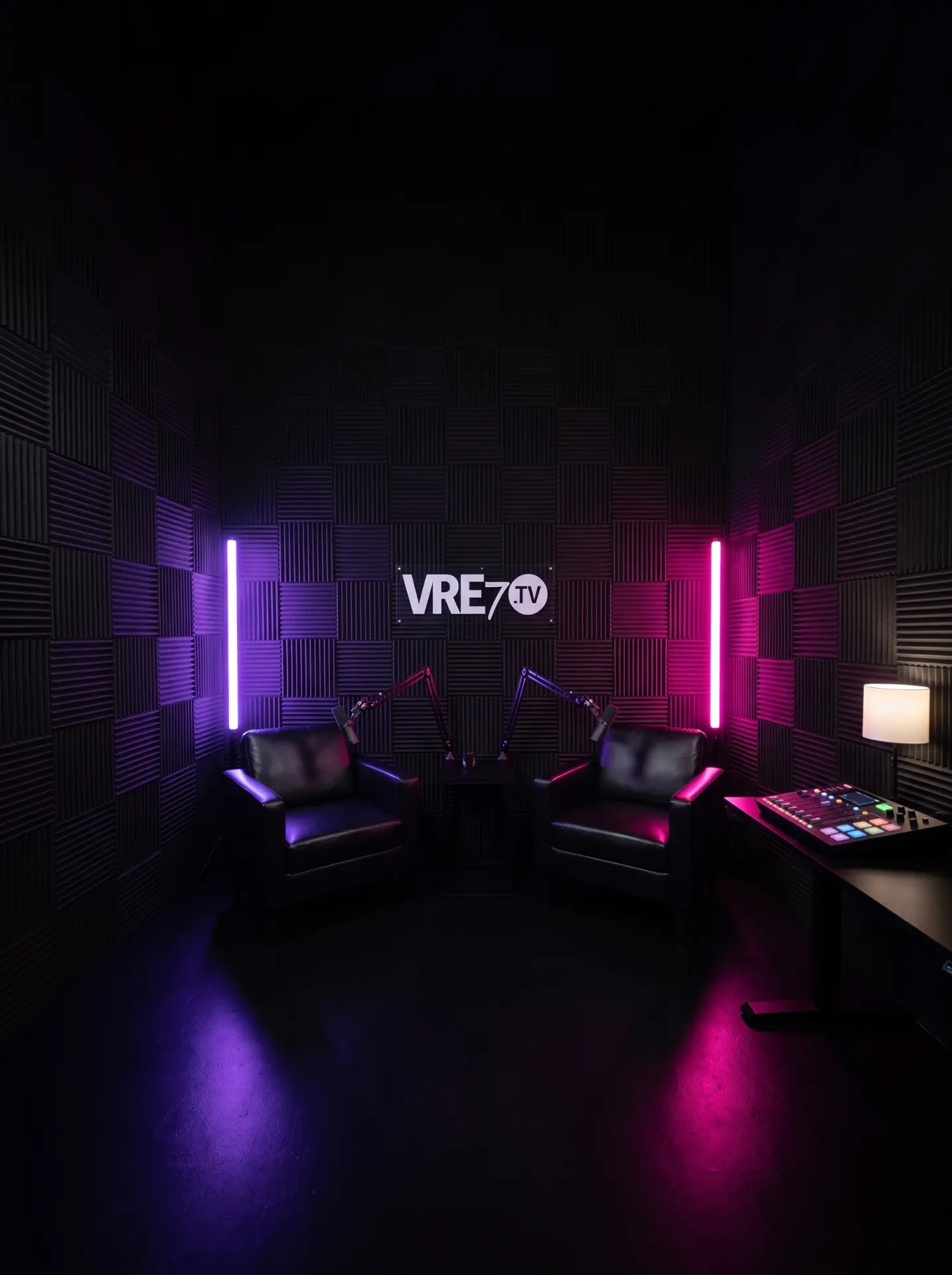 The VRE7 TV studio: two leather armchairs with boom microphones against an acoustic-panel wall with the VRE7.TV logo and purple and pink neon lighting